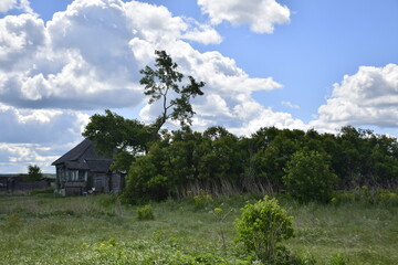 Plakat An old ruined wooden farmhouse against a clear sky with clouds. Ulyanovsk Russia.