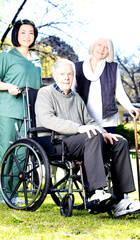 Elder people with wheelchair assisted by nurse outdoor