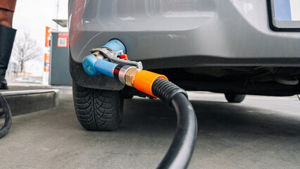 Gas station. Pump fuel petrol in tank car. Gasoline oil in nozzle. Close-up of the hand and the fuel gun. Blurred background.