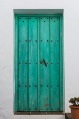 Vintage, green door with black studs and knob in Frigiliana. Malaga, Andalusia, Spain