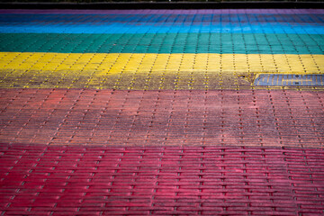 A fragment of the street paved in the colors of the rainbow - obrazy, fototapety, plakaty