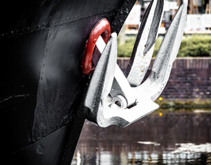 A silver anchor on the black bow of an old barge © Joanna