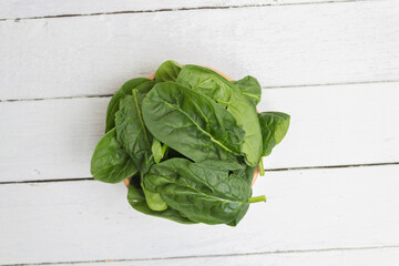 top view of organic spinach leaves in bowl on white boards