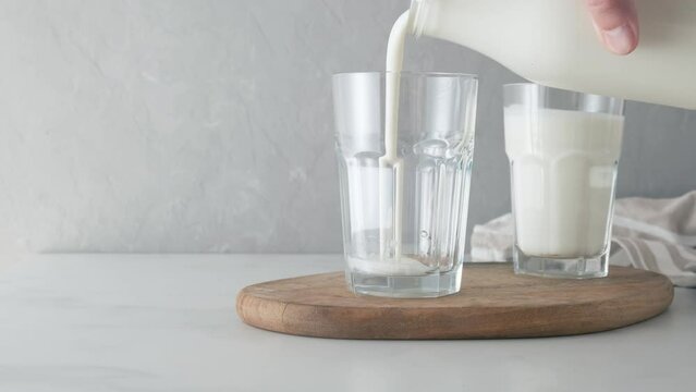 Pouring yogurt or kefir into glass cup. Glass with kefir or soured milk. Dairy products concept. 4k video