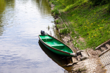 Angler boat moored on a grassy bank on a sunny day. Summer.