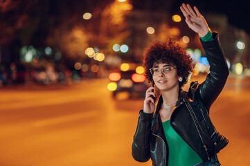 Woman calling a taxi while standing on road in city
