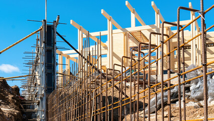 Rebar for concreting a fence at the construction site of a private house outside the city. Iron reinforcing bars are tied for the fence foundation frame or carcass. The use of formwork when concreting