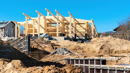 Fototapeta premium Construction site of a wooden house made of double profiled timber. The use of formwork when concreting the foundation of the fence. Building sand and sand-gravel mixture at the construction site.