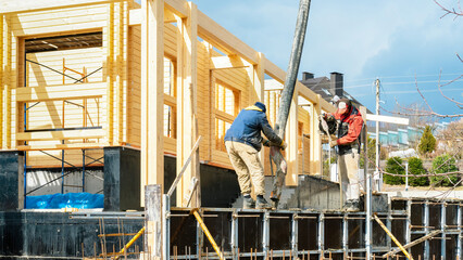 Workers concrete the retaining wall and foundation for the terrace using formwork and scaffolding....