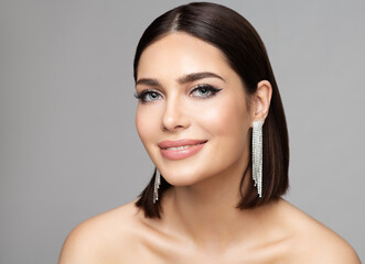 Beauty Woman Portrait with Perfect Make up and Silver Earrings. Smiling Fashion Model with Bob Haircut over Gray. Women Full Lips Gloss Makeup and Diamond Jewelry - obrazy, fototapety, plakaty