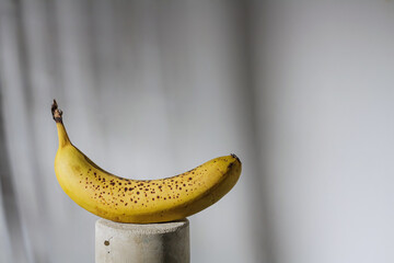 ripe yellow banana on grey stand in harsh light, copy space. Lunch time, eating disorder concept