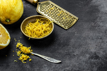 Yellow Organic lemons, zest and special tool. Grater peel and lemon zest on black background, banner, menu, recipe place for text, top view