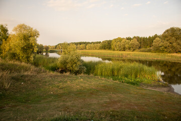 Beautiful autumn nature landscape view. Small river along field merging to blue sky.