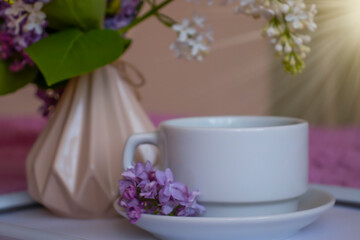 Fototapeta na wymiar cup of coffee, lilac flower in the apartment