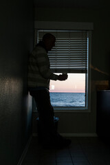 Fototapeta na wymiar Norfolk, Virginia, USA A man drinks coffee alone in a motel room by the sea.
