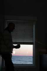 Norfolk, Virginia, USA A man drinks coffee alone in a motel room by the sea.