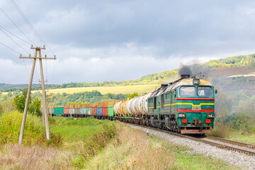 A green locomotive pulls a train loaded with gasoline and timber to the railway station. Carpathian...