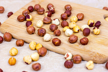 Peeled brown hazelnuts on wooden board and textile background.