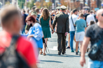 Ukrainian military man with woman holding hands on busy city street with crowd of people