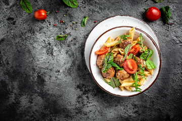 penne pasta with meatballs and spicy tomato sauce on a dark background. Restaurant menu, dieting, cookbook recipe banner, place for text, top view