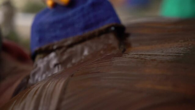 Beautician giving chocolate massage to young man in luxury spa. The masseur rubs chocolate cream into the back and shoulders