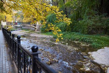 Small river flows in a beautiful autumn park in the city center