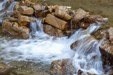 Small stream of water flows through a barrier from large stones