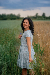 woman is standing  in a field of wheat and smiling 