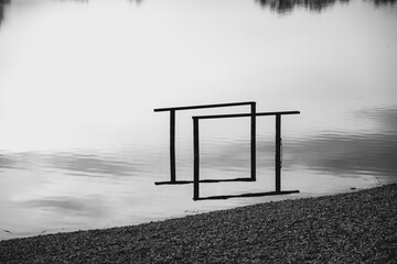 Steel structures standing in the shallow water, reflected in the surface, creating rectangular shape in process