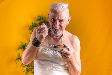 handsome middle aged man standing eating a slice of chocolate cake - colored background studio shot