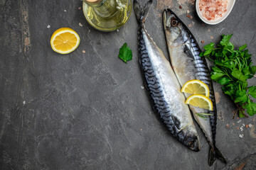 Raw Mackerel fish with salt, lemon and spices on dark background. Fresh seafood. Culinary, cooking...