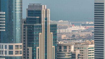 Skyscrapers of Dubai with a lot of ships in port behind aerial timelapse