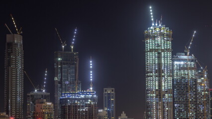 Fototapeta na wymiar High multi-storey buildings under construction and cranes at night timelapse