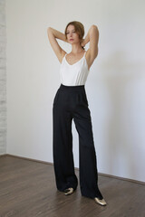 Female model wearing white camisole cotton top and black trousers. Classic and simple summer...