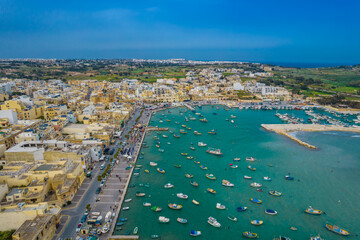 Aerial panoramic view of Marsaxlokk - small, traditional fishing village in the South Eastern Region of Malta with many colorful fisherman boats in the bay