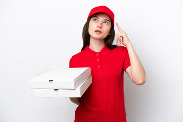 Young Russian pizza delivery picking up pizza boxes isolated on white background having doubts and...