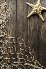Fishing net and starfish on old oak board background with copy space - obrazy, fototapety, plakaty