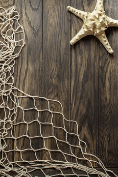 Fishing net and starfish on old oak board background with copy space