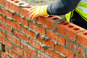 Bricklayer laying bricks on mortar on new residential house construction. Get skiils in briklaying concept