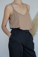 Female model wearing beige camisole cotton top and black trousers. Classic and simple summer...