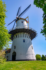Beautiful white windmill in the countryside with green grass on a bright sunny day 
