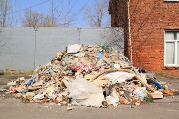 Unauthorized illegal dump unsorted pile of domestic garbage concept. Environmental serious ecological problem. Trash landfill. Сonstruction debris on the street of a city. Waste management industry.
