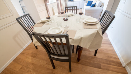 Living room with dining table with silverware and red wine glasses in a modern and bright apartment