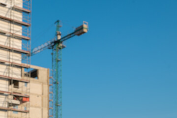 Blurred modern apartment building under construction. Sunny day with blue sky.