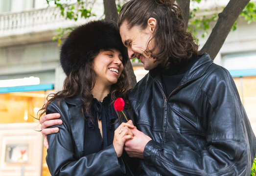 Cheerful couple with flower on street