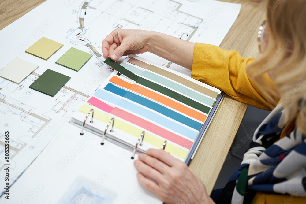 Poster close-up of a designer sitting at a table with color palette and choosing colors for new interior
