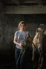 Fototapeta na wymiar A young beautiful female worker takes care of a horse on a farm.