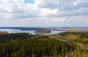 Top view from a quadrocopter of a spring green forest over a lake