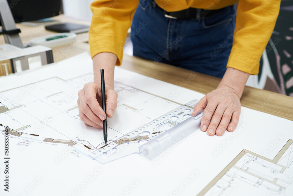 Poster Close-up of architect using pencil and ruler to draw blueprint on table at office