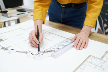 Close-up of architect using pencil and ruler to draw blueprint on table at office